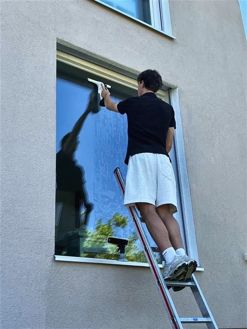 Grutani bei der Reinigung eines Aussenfensters auf der Leiter